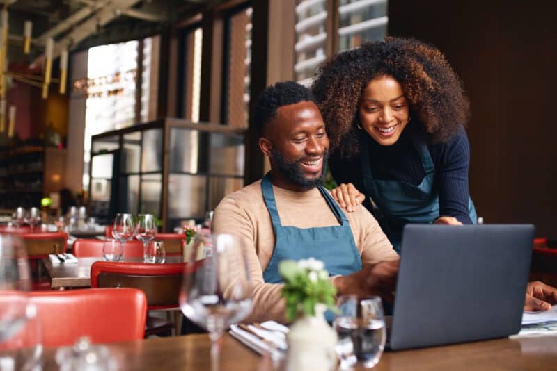 restaurant owners reviewing management system on laptop