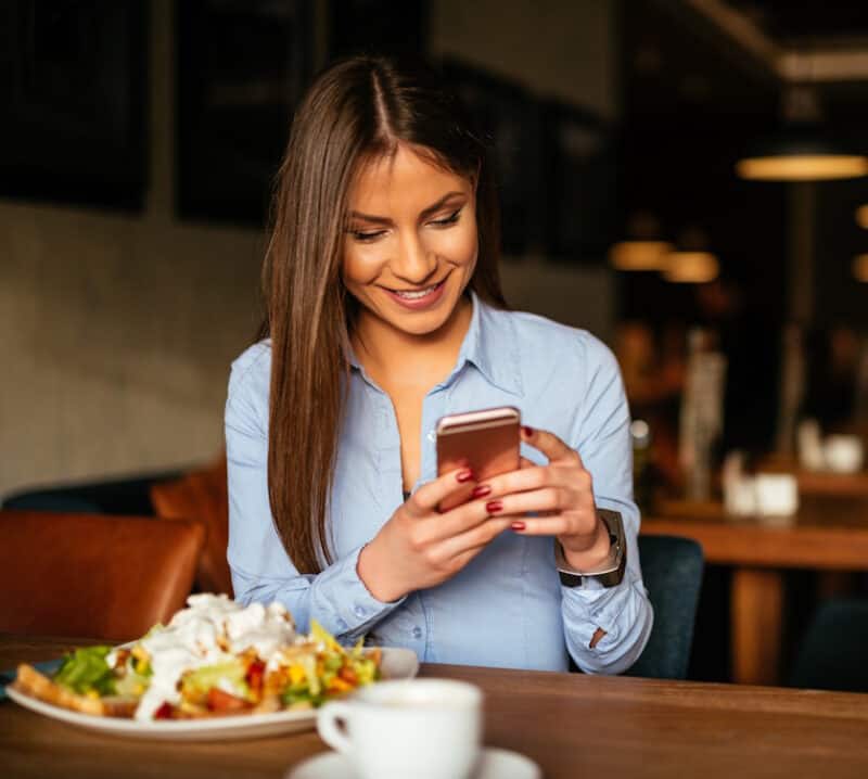 woman searching on phone at restaurant